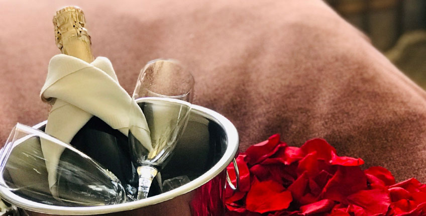 Rosenblade på sengen og mousserende vin giver romantikken gode vilkår